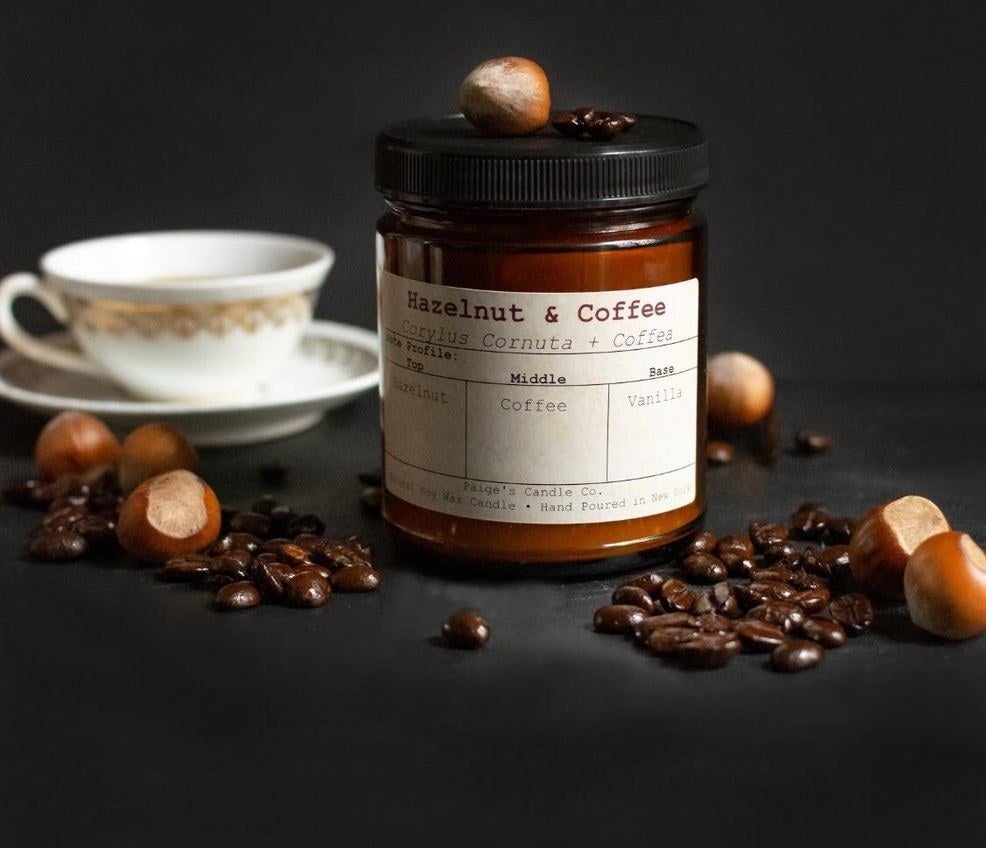 Candle surrounded by hazelnuts and coffee beans