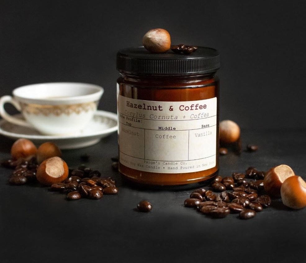 Candle surrounded by hazelnuts and coffee beans