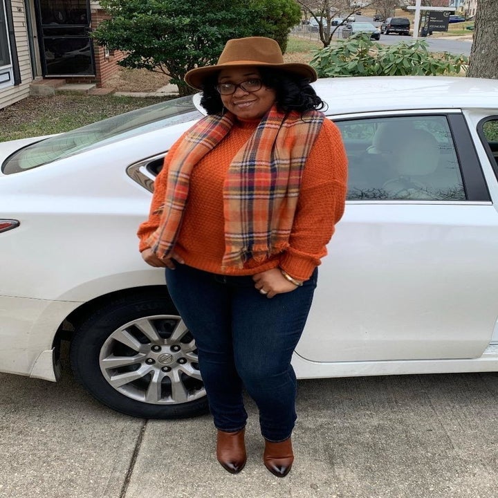 A reviewer wearing the sweater in orange