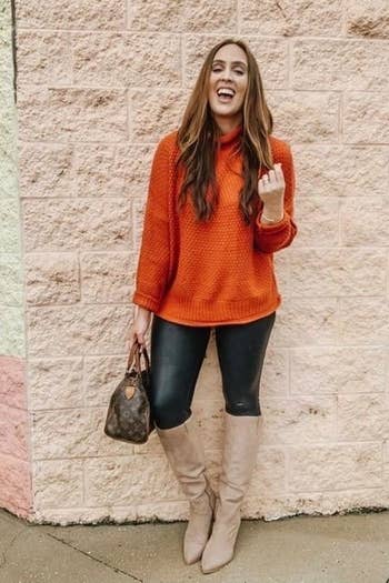 A different reviewer wearing the sweater in orange