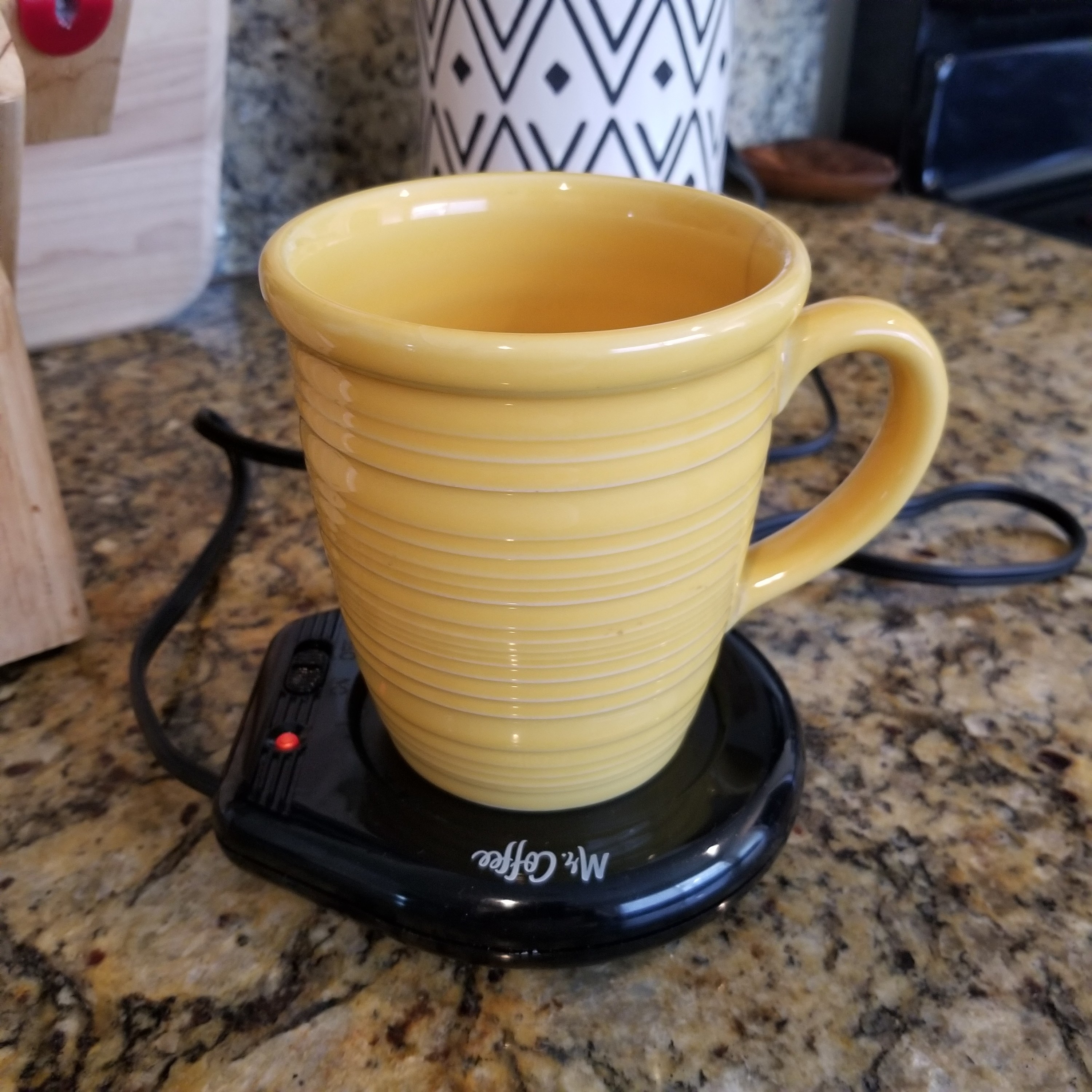 A yellow mug placed on top of the mug warmer