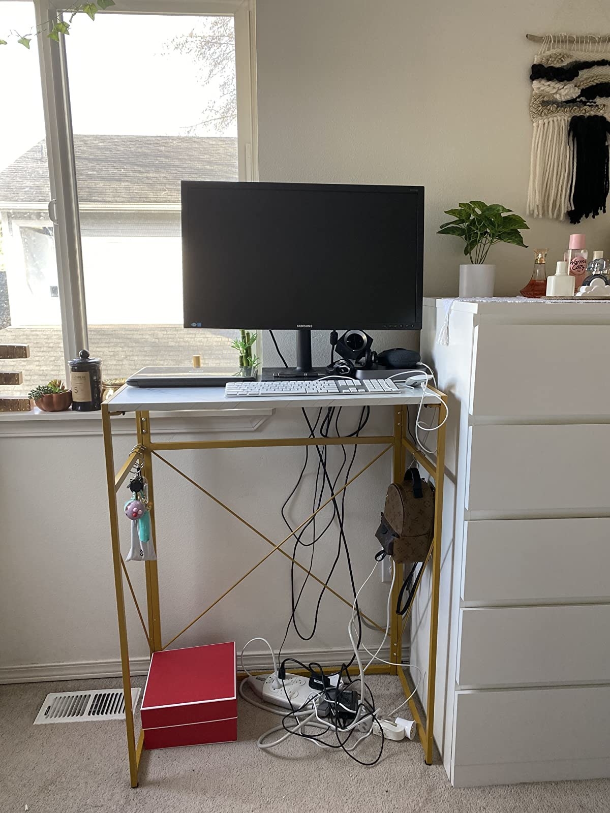 reviewer image of the Mr IRONSTONE Folding Standing Desk next to a dresser in a bedroom