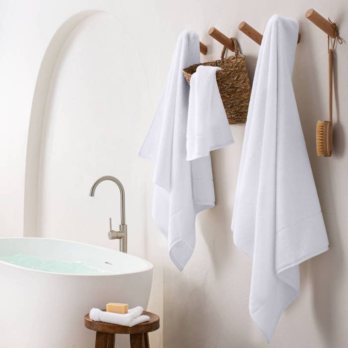Four sizes of the towel hanging in a bathroom, shown in white.