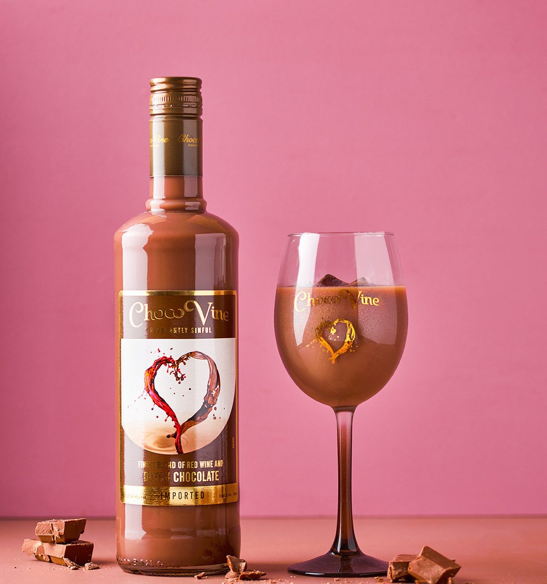 Bottle of ChocoVine next to a wine glass filled with the chocolate wine drink