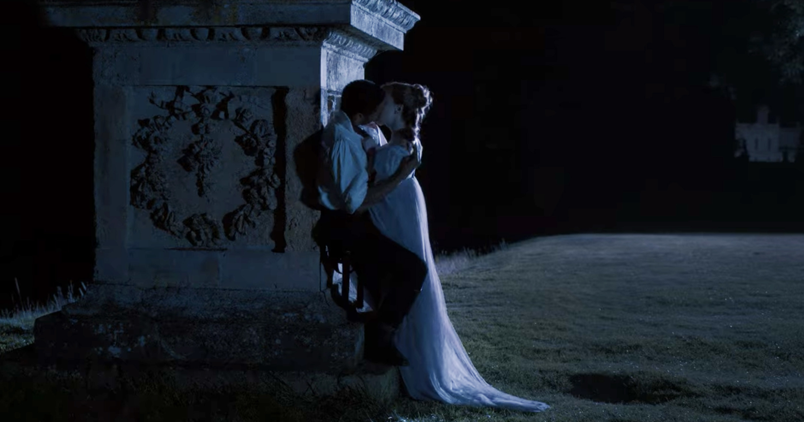 Simon and Daphne passionately kissing against a statue outside