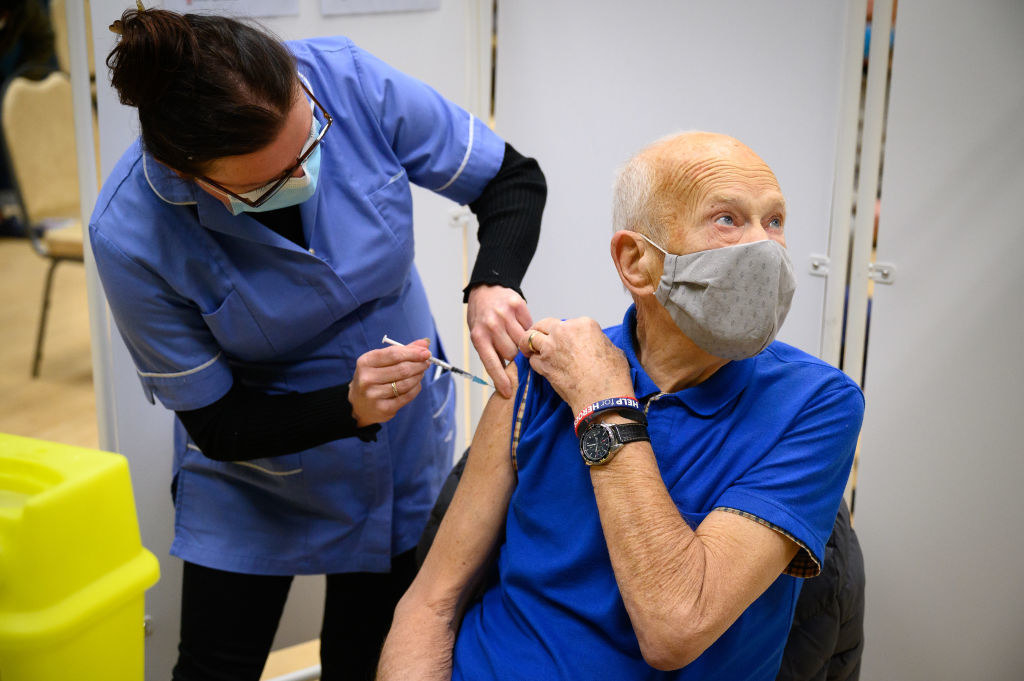 An older man looking away as he receives the vaccine