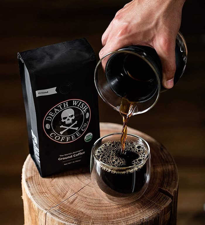 bag of coffee with a skull and crossbones on it next to someone pouring coffee into a mug