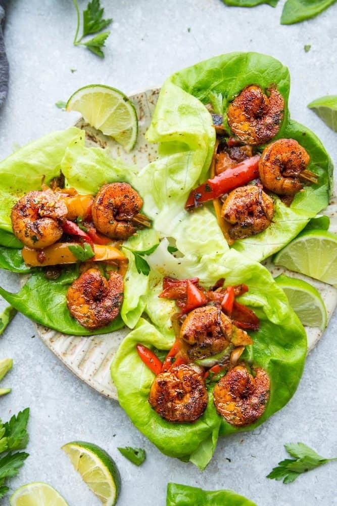 Several lettuce wraps filled with spiced shrimp and peppers. 