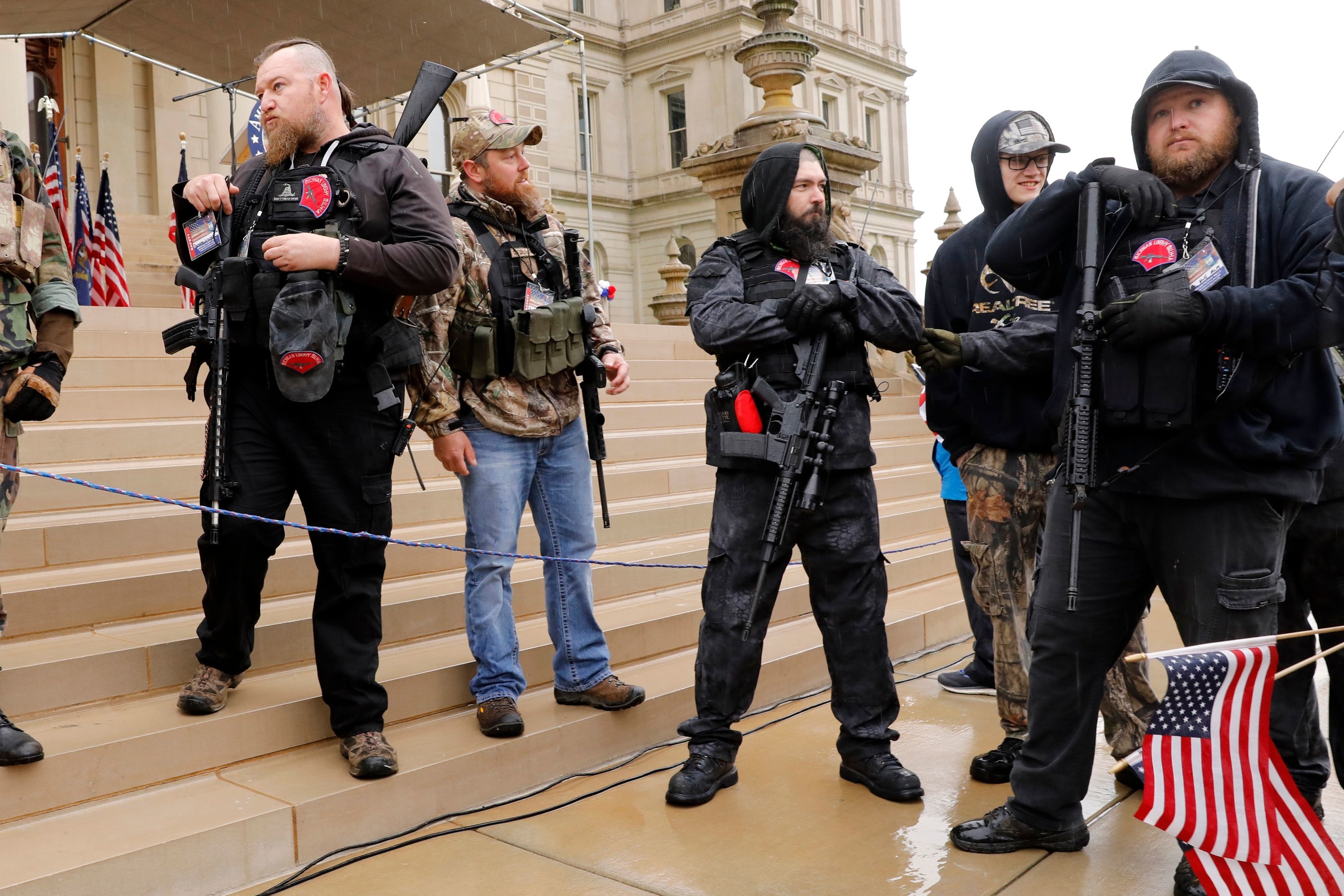 White men armed with large guns stand on the steps outside the state capitol building