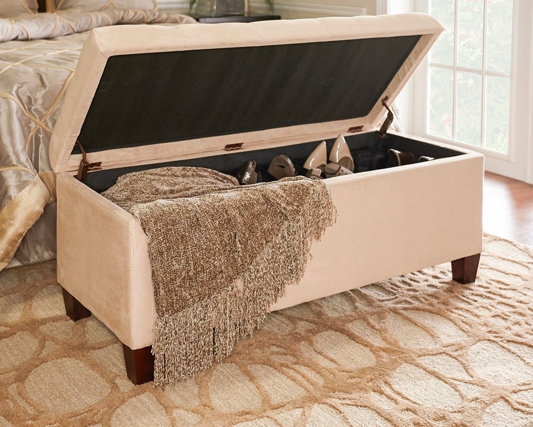 beige ottoman with square wood legs, lid open revealing the shoe collection