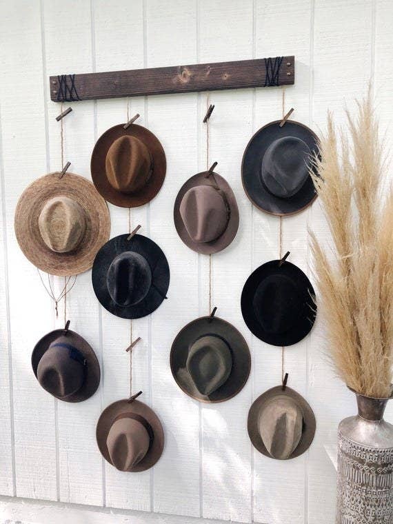 Hanging hat organizer with colorful fedoras clipped to pins on dangling ropes