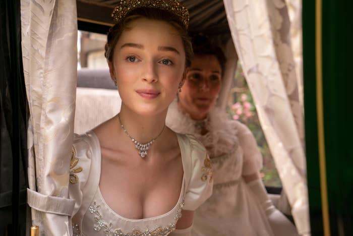 Phoebe Dynevor as Daphne Bridgerton and Ruth Gemmell as Viscountess Bridgerton riding in a carriage