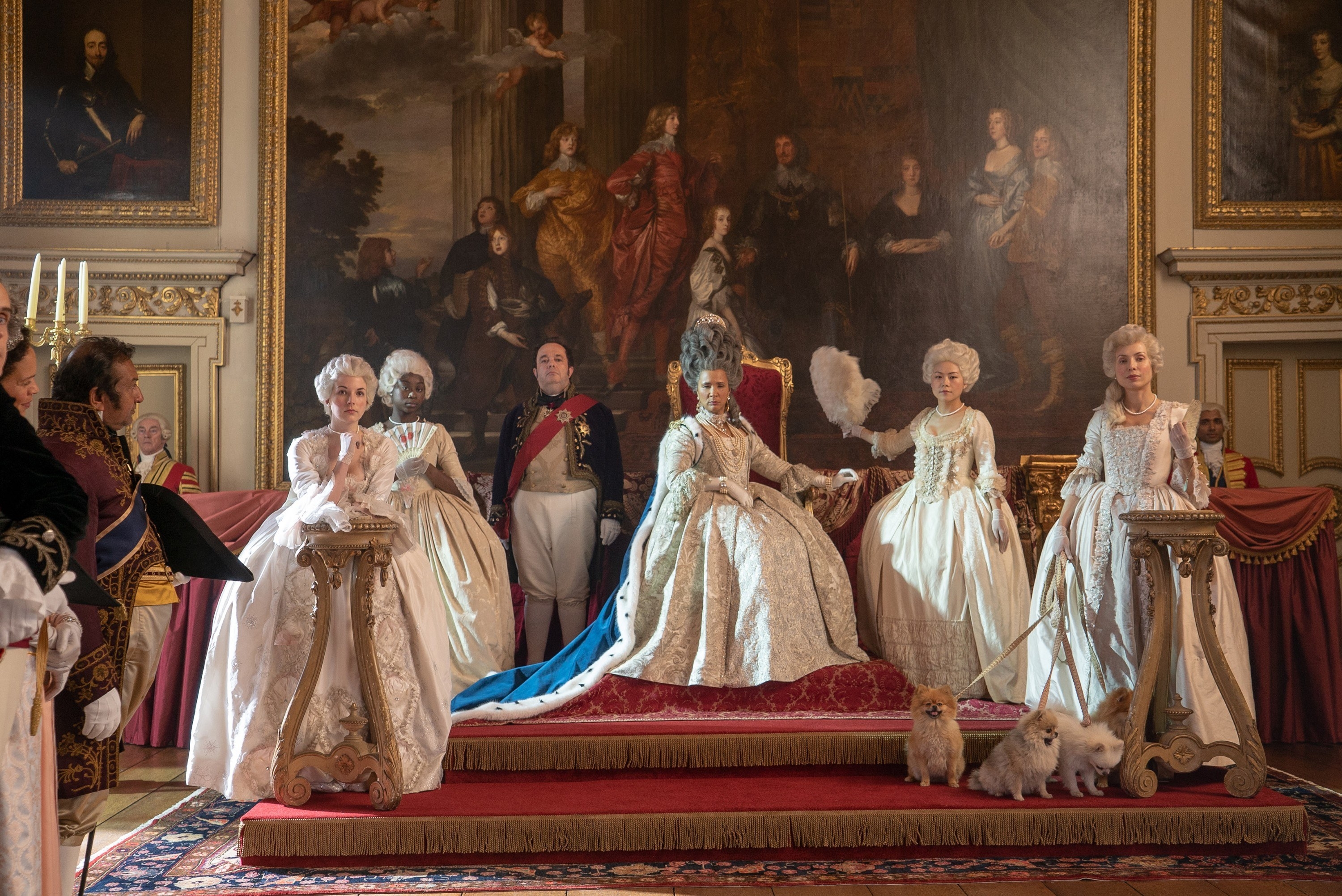 Golda Rosheuvel as Queen Charlotte sits on a throne surrounded by ladies-in-waiting and servants 
