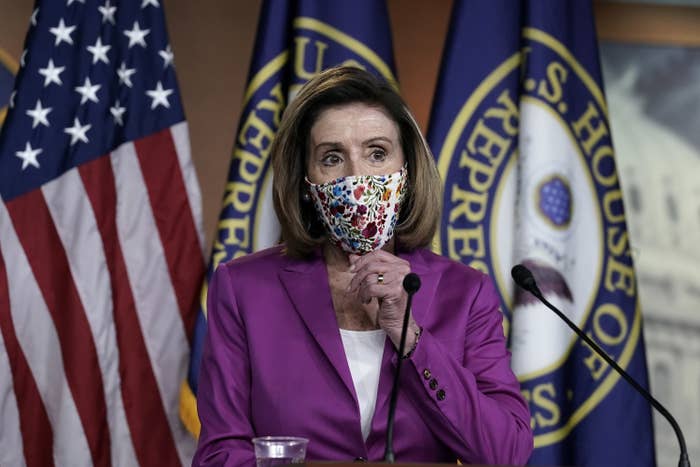 Nancy Pelosi adjusts her face mask