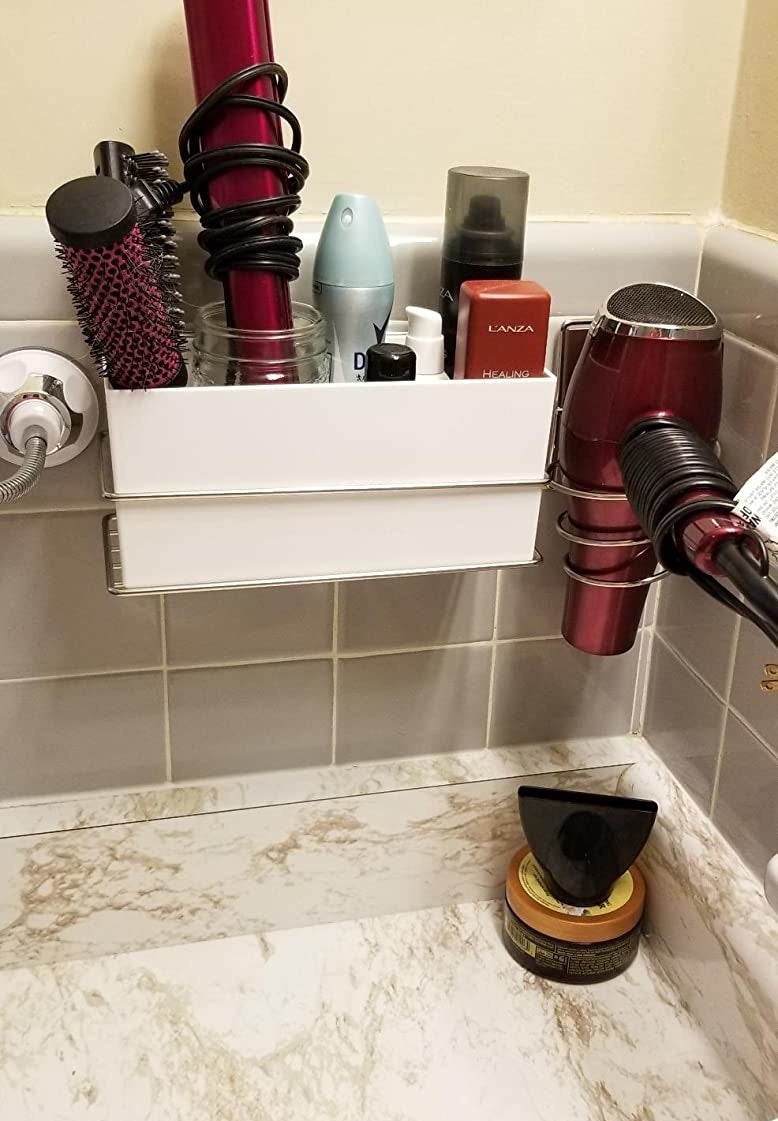 reviewer image of the rectangular-shaped container attached to the wall above a counter that&#x27;s filled with assorted hair and body products