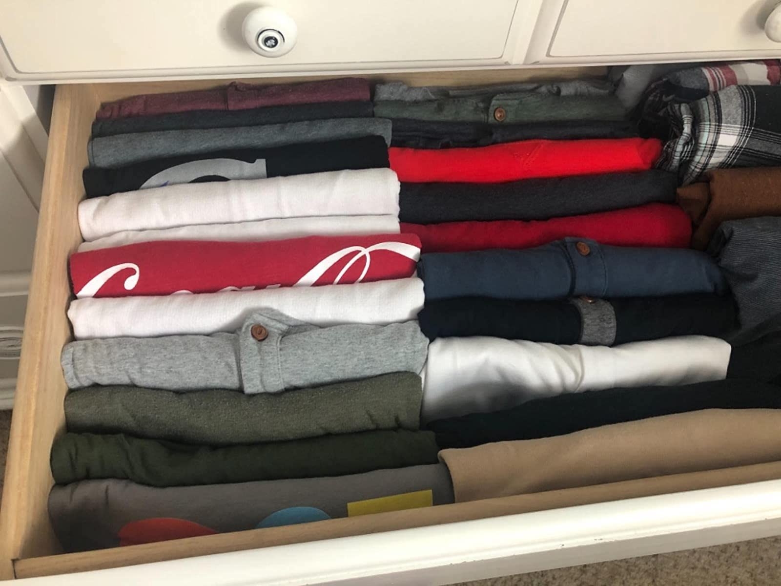reviewer image showing their drawer organized with shirts perfectly folded with the folding board 