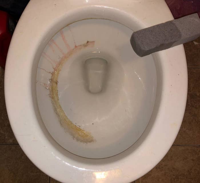 reviewer photo showing toilet half cleaned with the pumice cleaning tool 