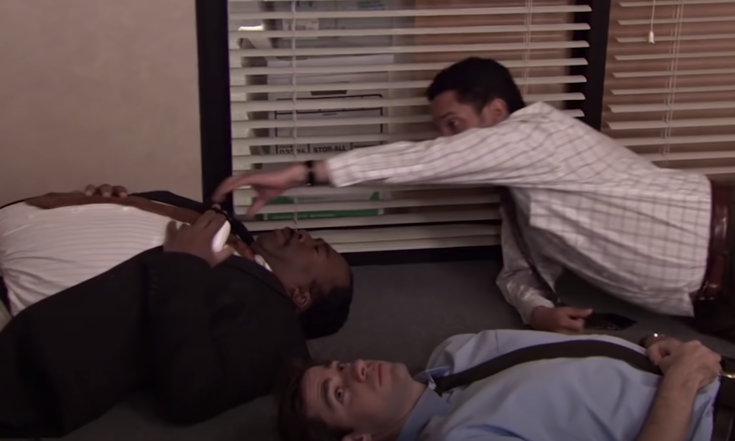 three men lay on the ground in an office, meditating. a man who is standing says &quot;oscar can you reach over and touch his thing&quot; while one of the laying down men grabs another&#x27;s tie