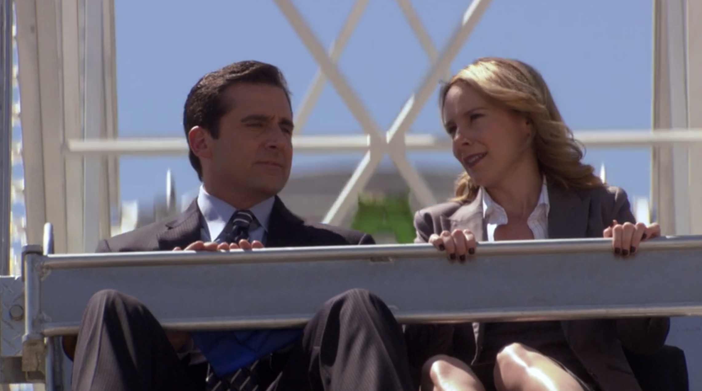 a man in a suit and tie and woman in a blazer ride a ferris wheel