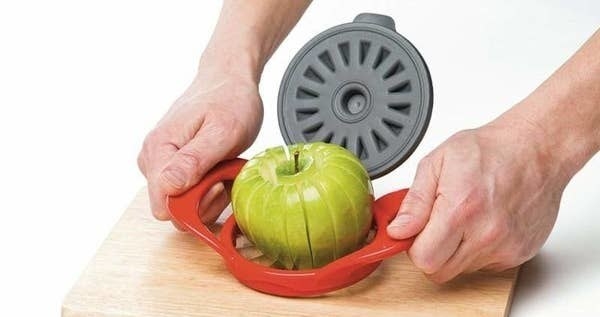 A person slicing an apple with the slicer/corer