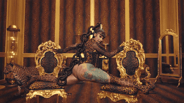 Cardi B doing the splits on two chairs with a leopard behind her in the WAP music video