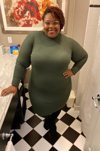 A reviewer wearing the long sleeve sweater dress in army green