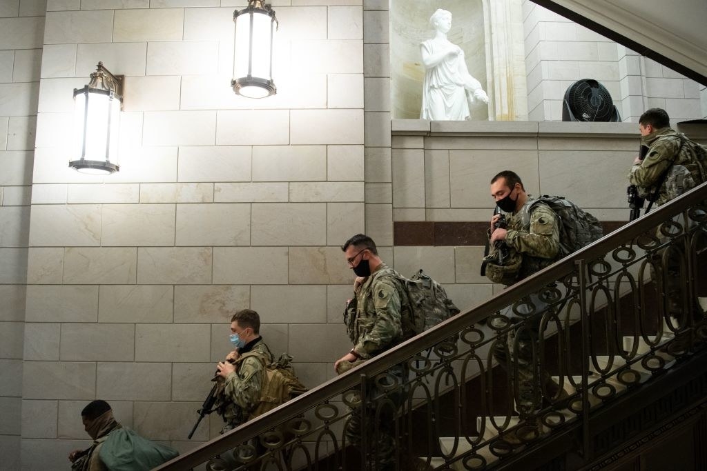 Armed National Guard members walk down a stairwell