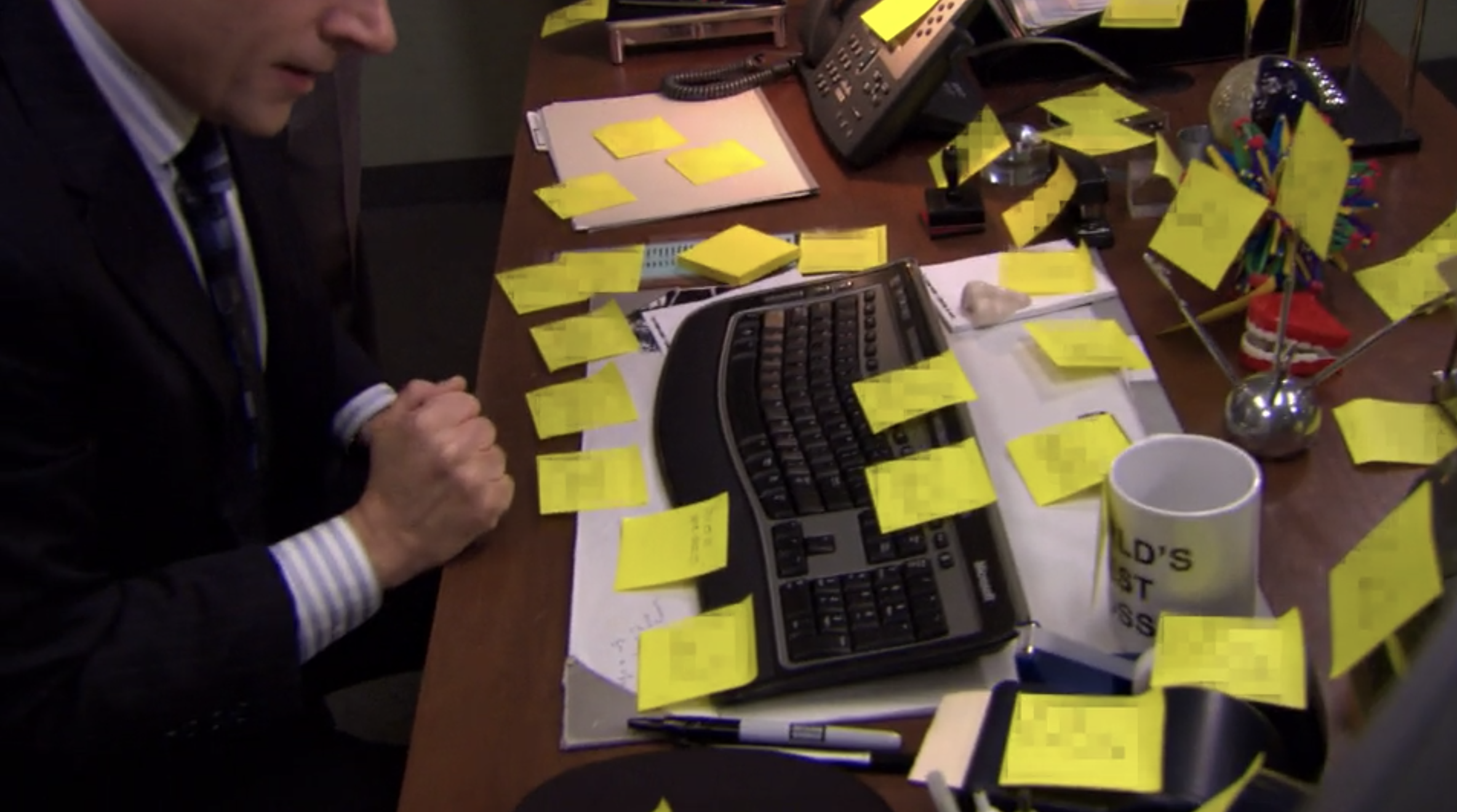 a man sits at a desk covered with post it notes