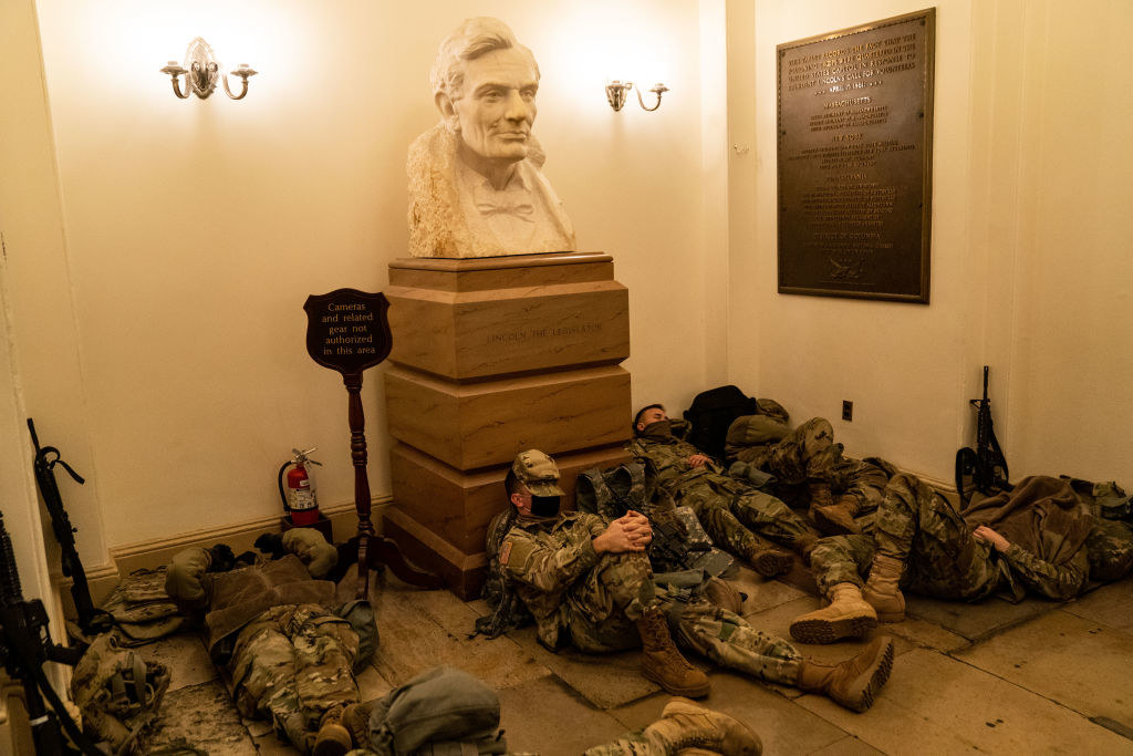 Armed National Guard members lie on the floor and against a bust of President Abraham Lincoln inside the Capitol