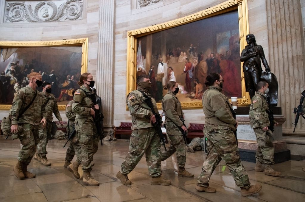 Armed National Guard members walk out of a room in the Capitol