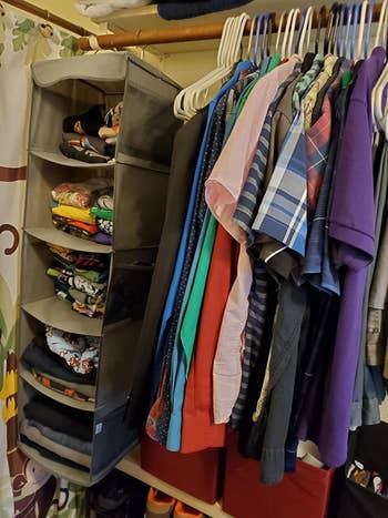 Same gray organizer with colorful folded tees and pants next to hanging polo shirts in a closet