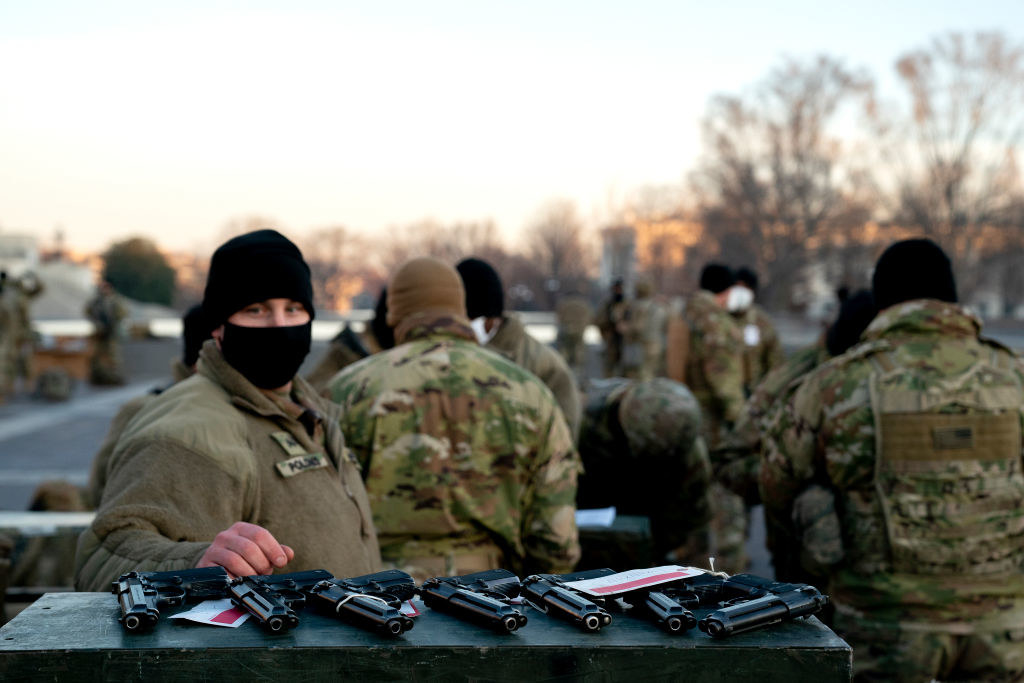 A National Guardsman looks at several guns laying in a row