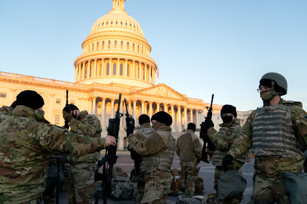 Several National Guard members holding their weapons as they stand outside of the Capitol