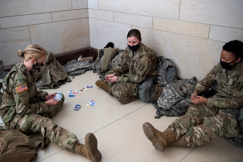 National Guard members play cards as they sit on the floor of the Capitol