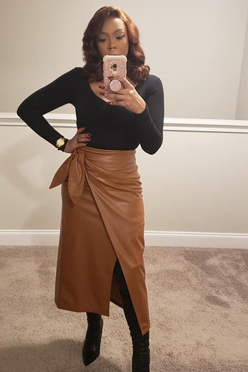 A reviewer wearing the skirt with a slit and a tie waist in brown