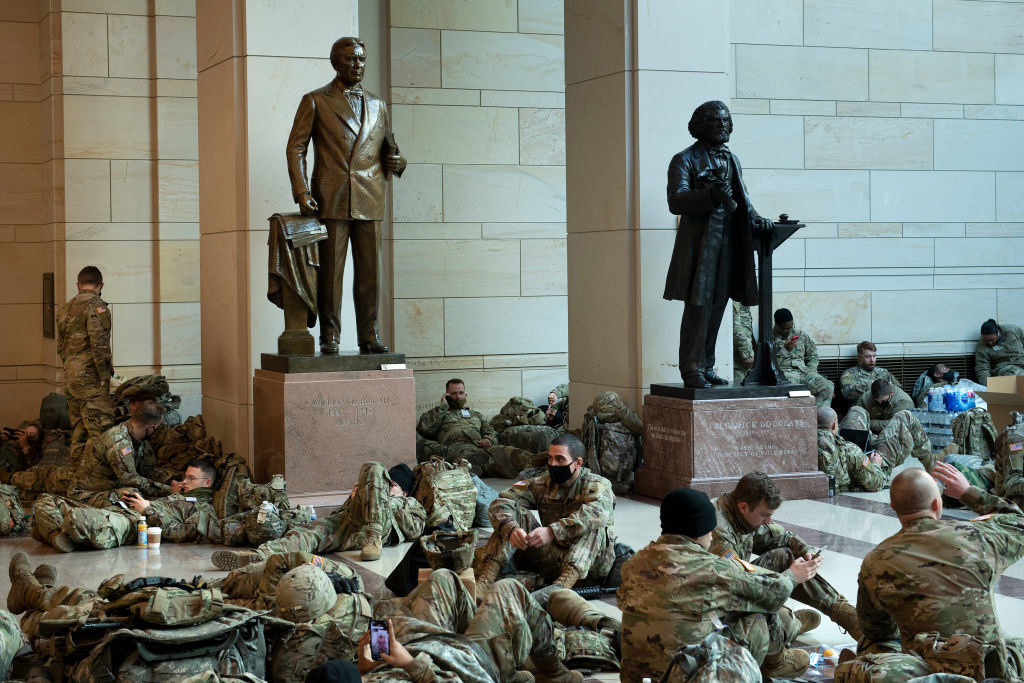 National Guard members sitting around two statues inside the Capitol