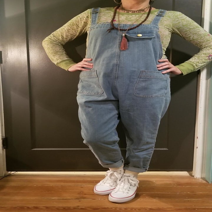 A reviewer wearing the light wash overalls