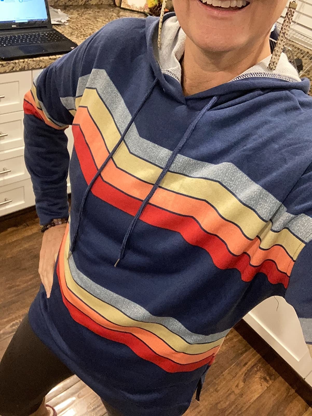 a reviewer wearing a navy sweatshirt with colored stripes vertically across the top and bottom