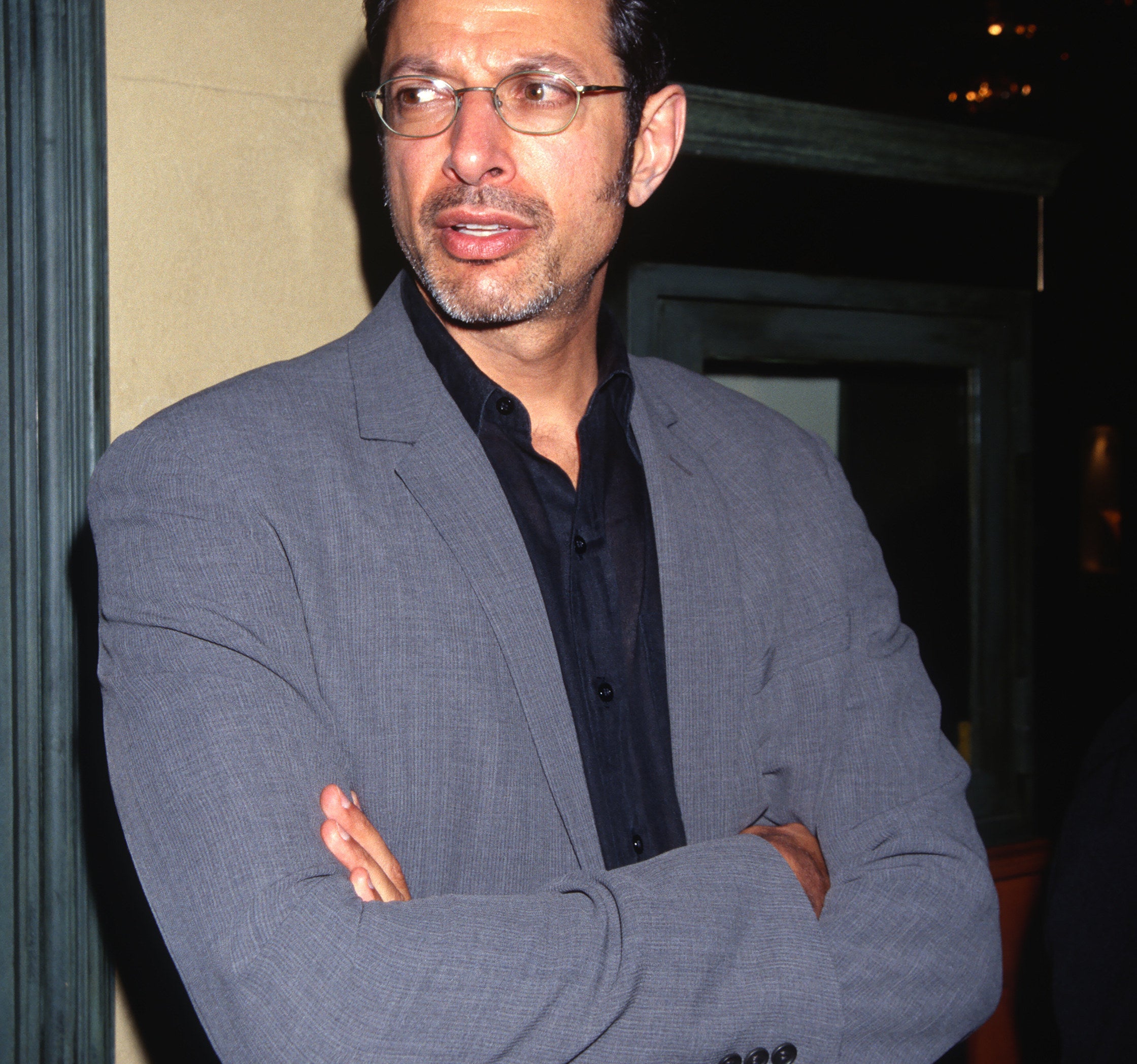 Jeff Goldblum wearing a grey suit and black shirt