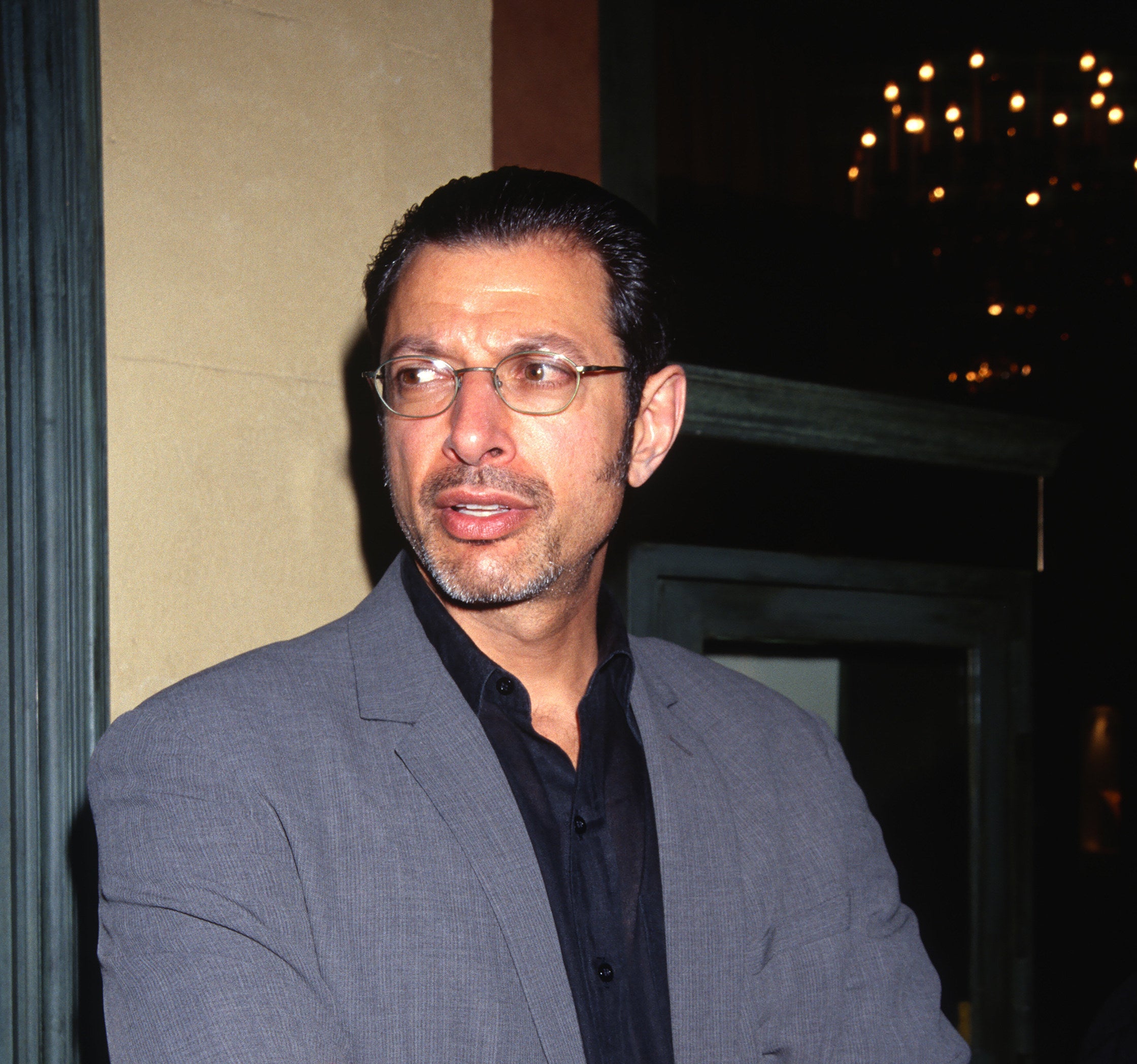 Jeff Goldblum wearing a grey suit and black shirt