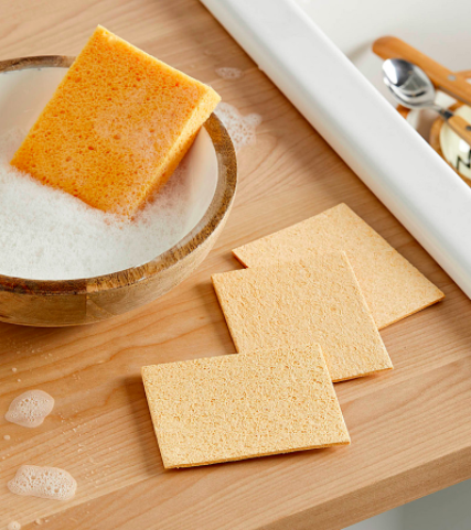 A trio of flat dish sponges next to a bowl of soapy water