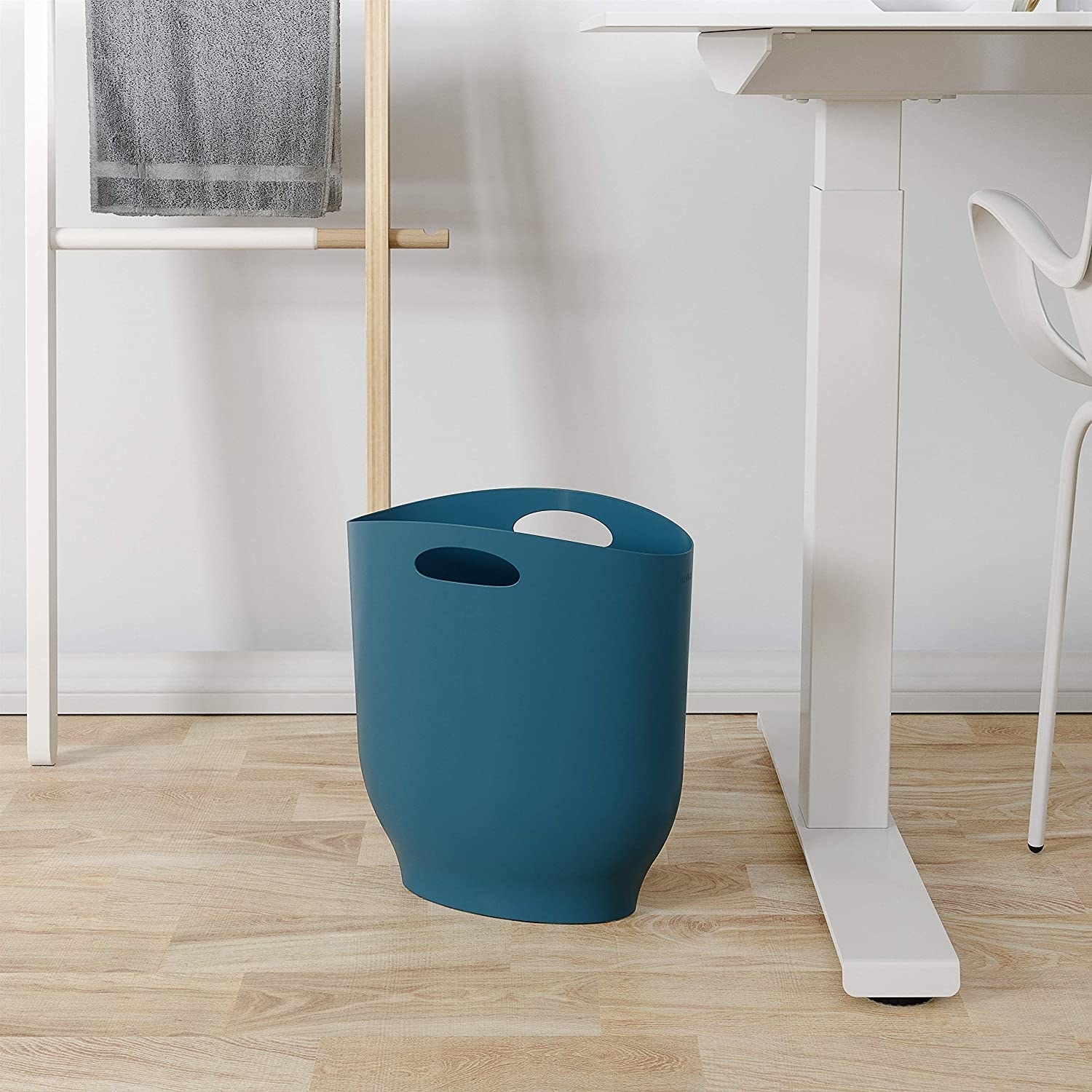A slim trash can next to a modern desk