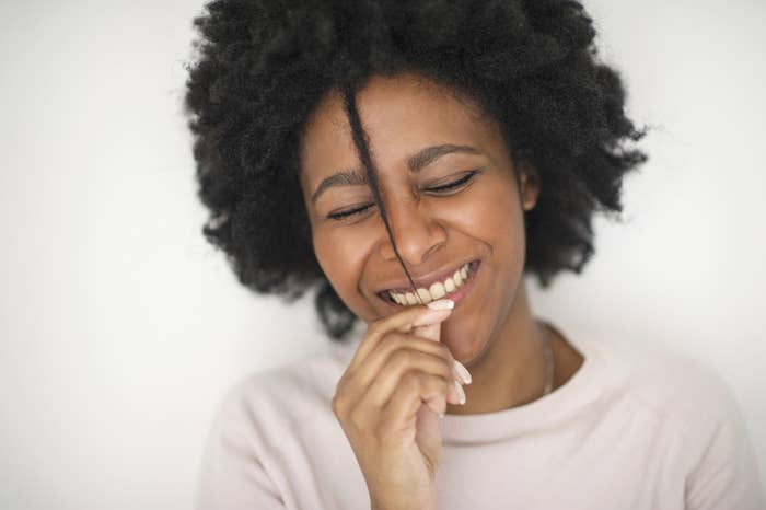 A woman with natural hair pulls on a strand of hair to show her shrinkage