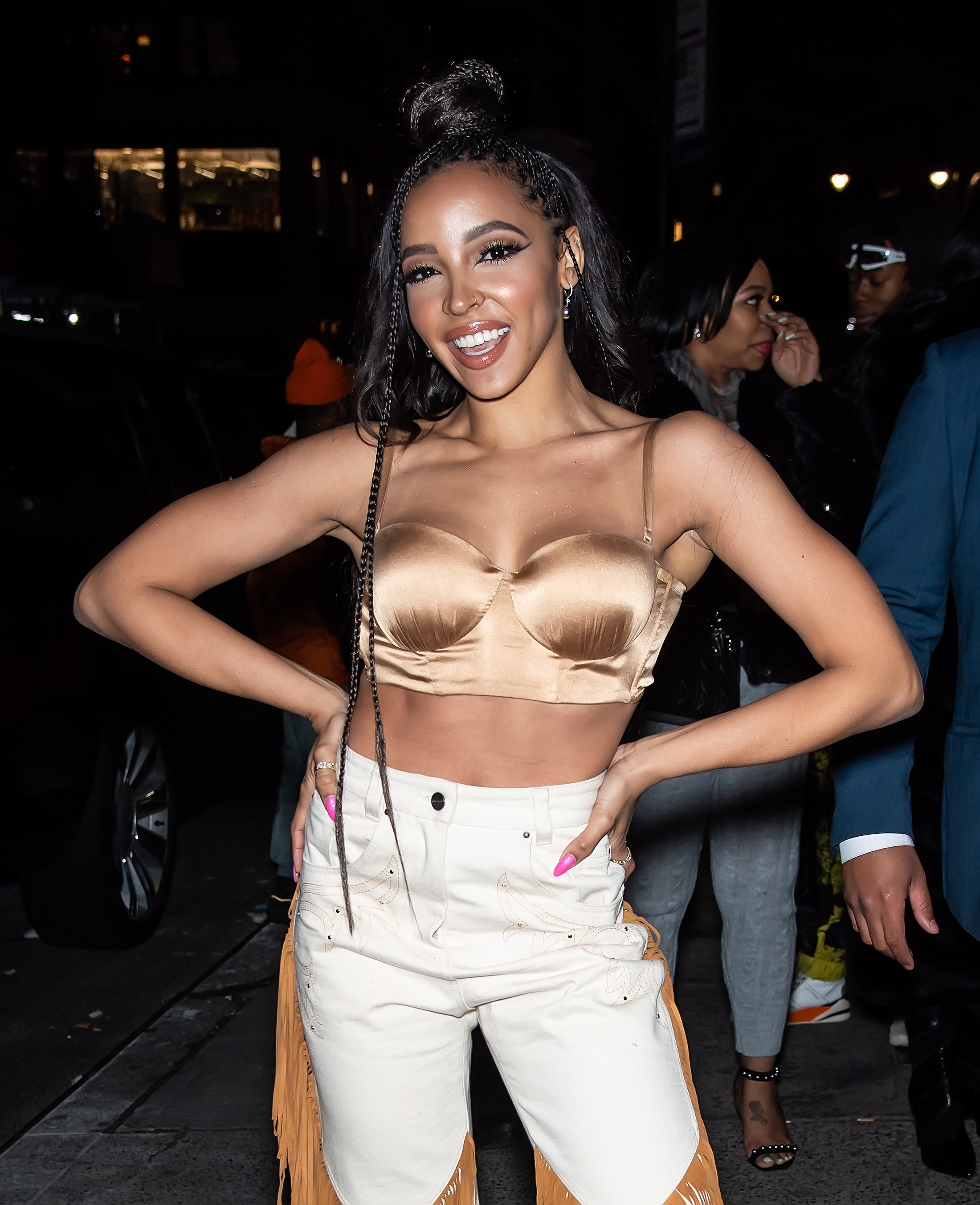 Tinashe outside a club in a bustier top and fringe white cowboy jeans