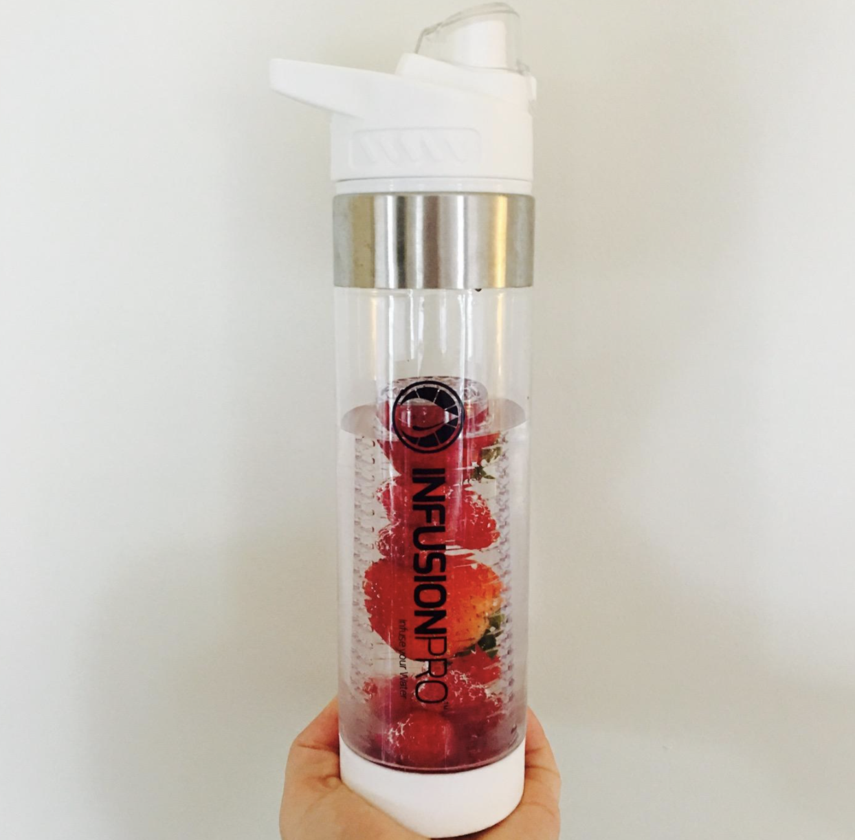 a reviewer holding the white bottle with strawberries and raspberries in the infuser 