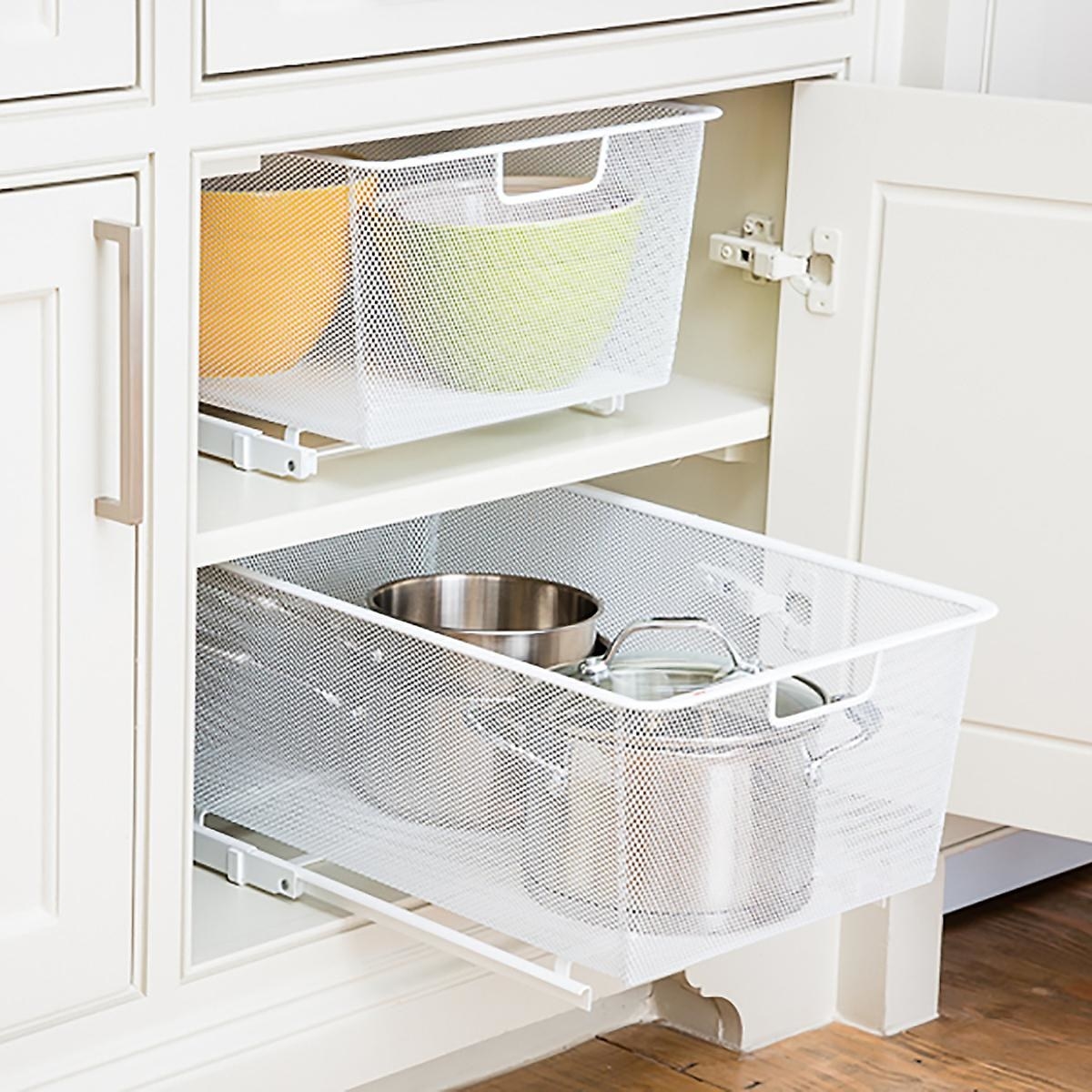 Sliding drawer placed in cabinet with various pots and pans inside