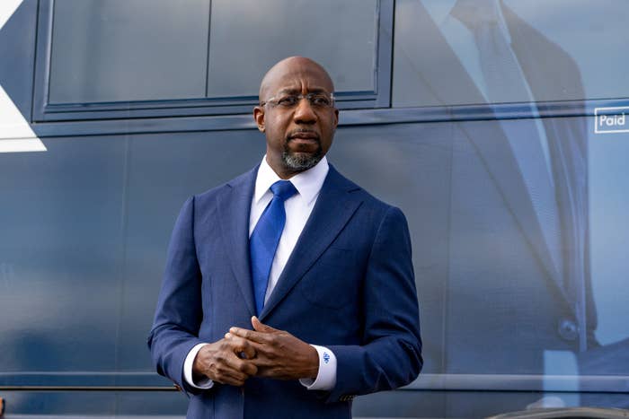 Raphael Warnock is shown wearing a suit and tie
