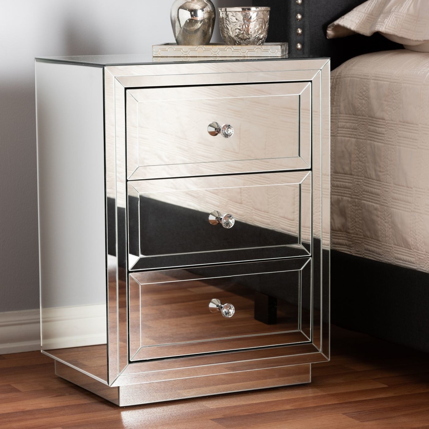 A three drawer mirrored nightstand with crystal knobs