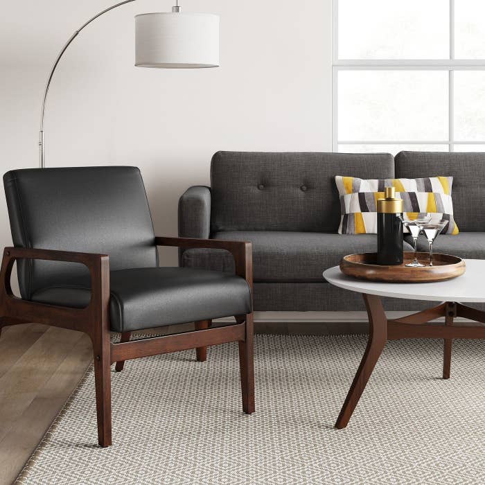 A black upholstered armchair with dark wood legs and arms