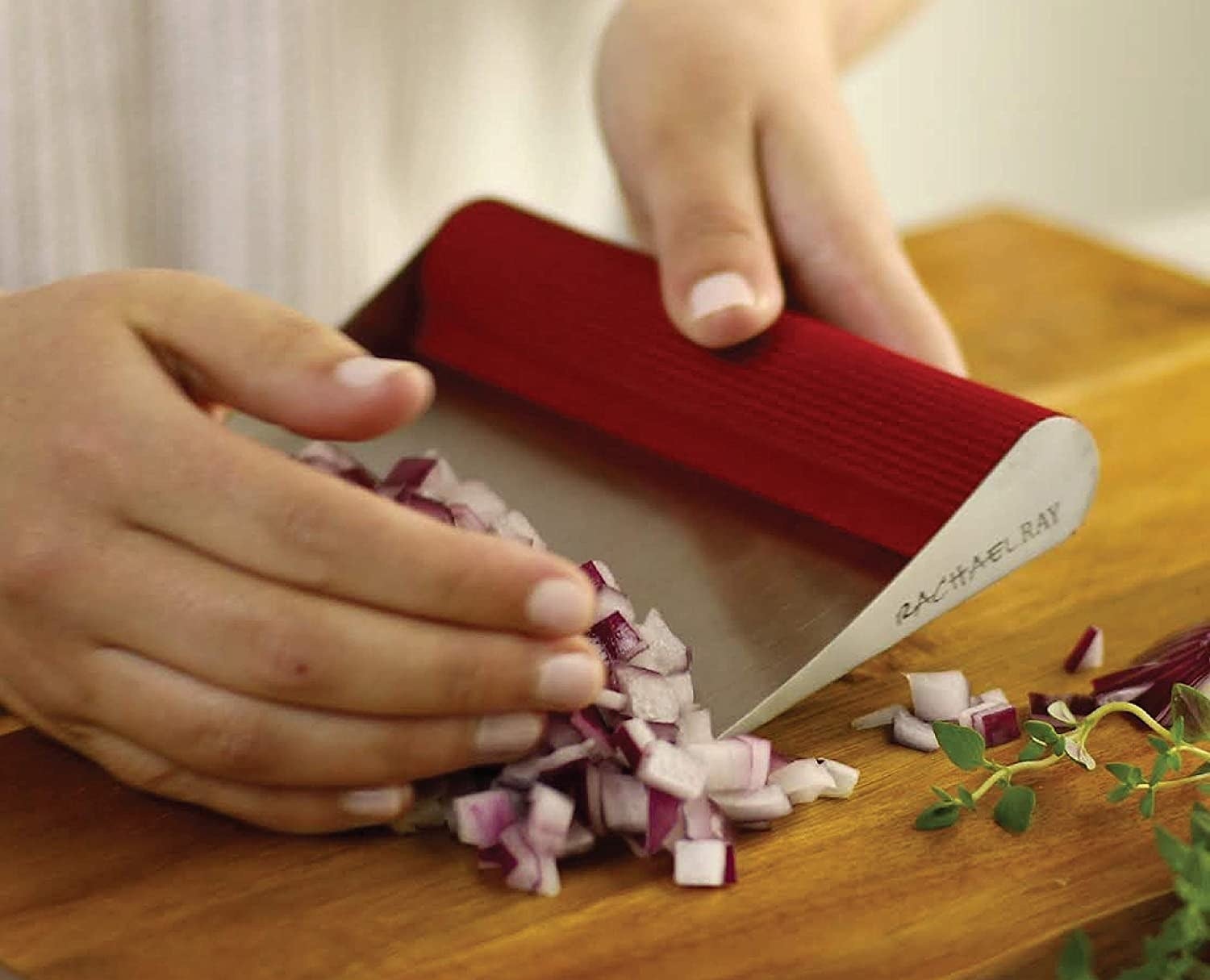 person using the scraper to pick up some chopped onions